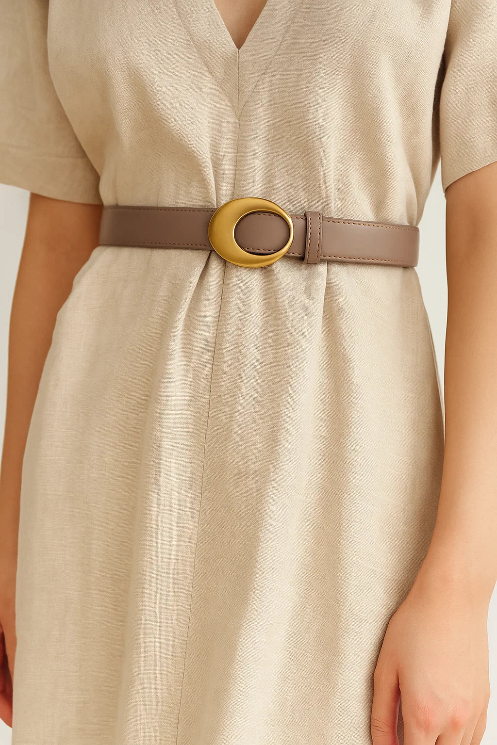 Beige dress with a belt featuring a gold buckle on a plain background