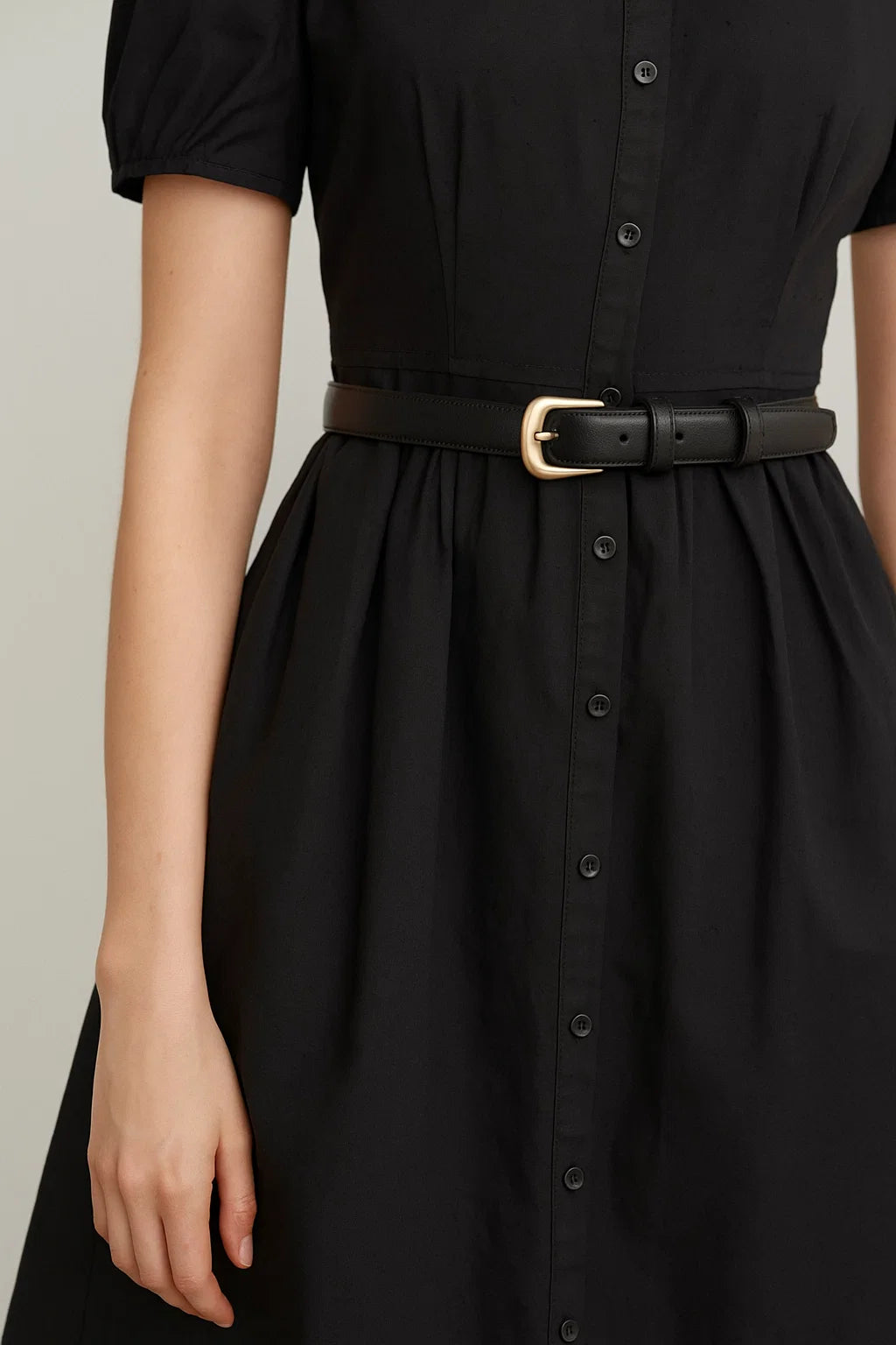 Black dress with a belt on a neutral background