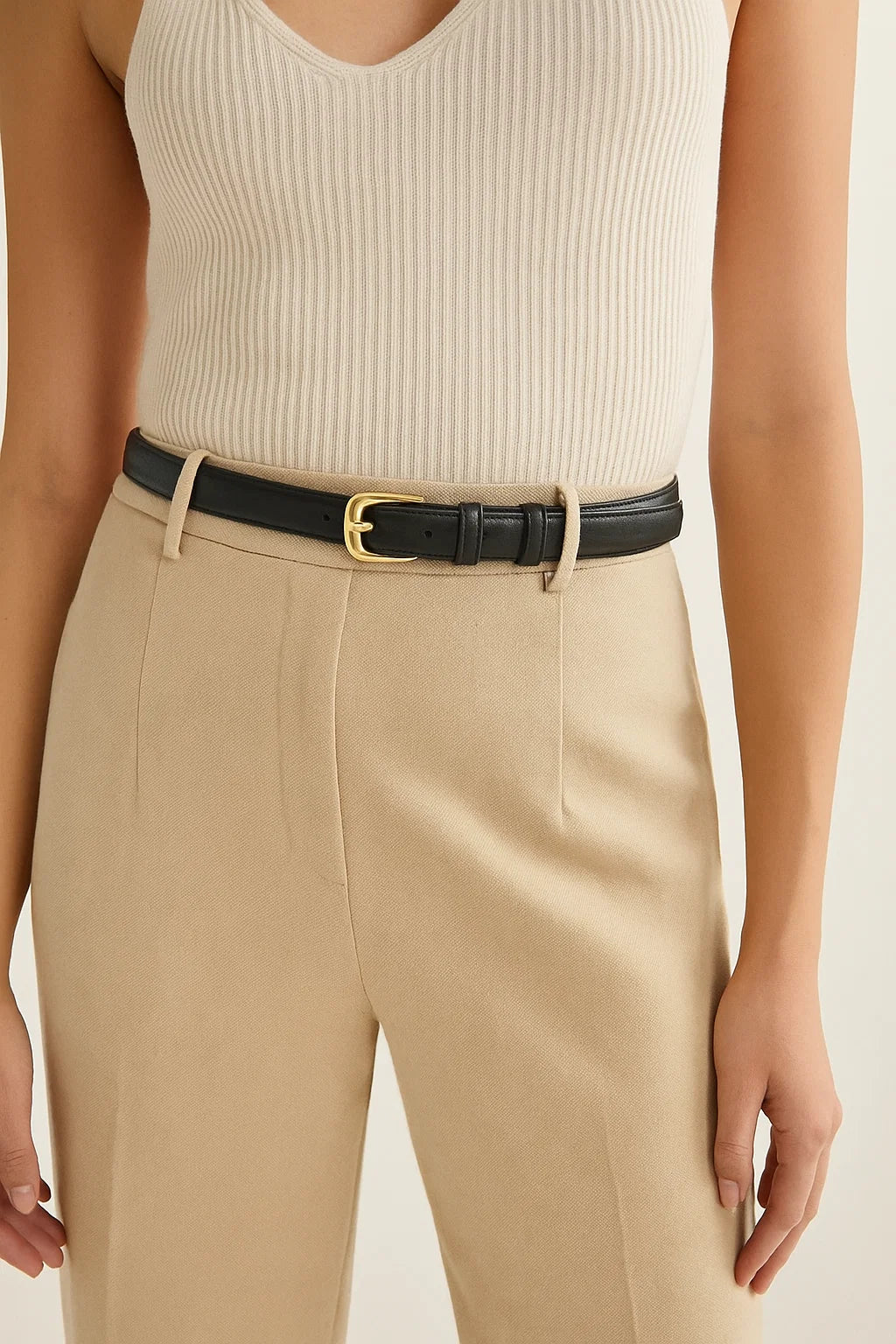 Women wearing a beige ribbed top and beige pants with a black belt.