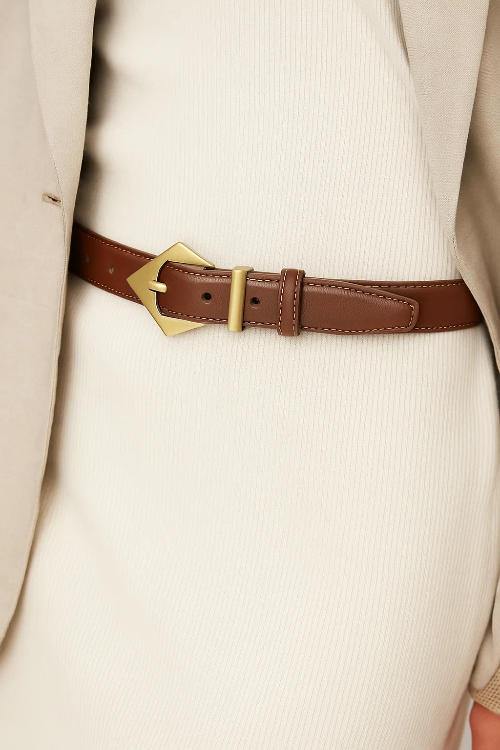 Brown leather belt with gold buckle worn by a person in a beige suit.